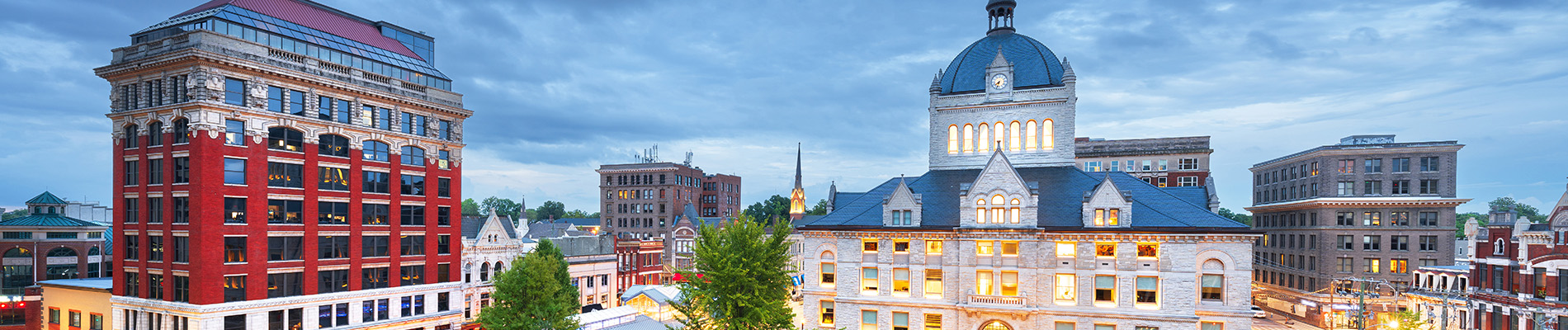 The image shows a cityscape with buildings under a sky, featuring a prominent dome building and a river running through the center of the town.