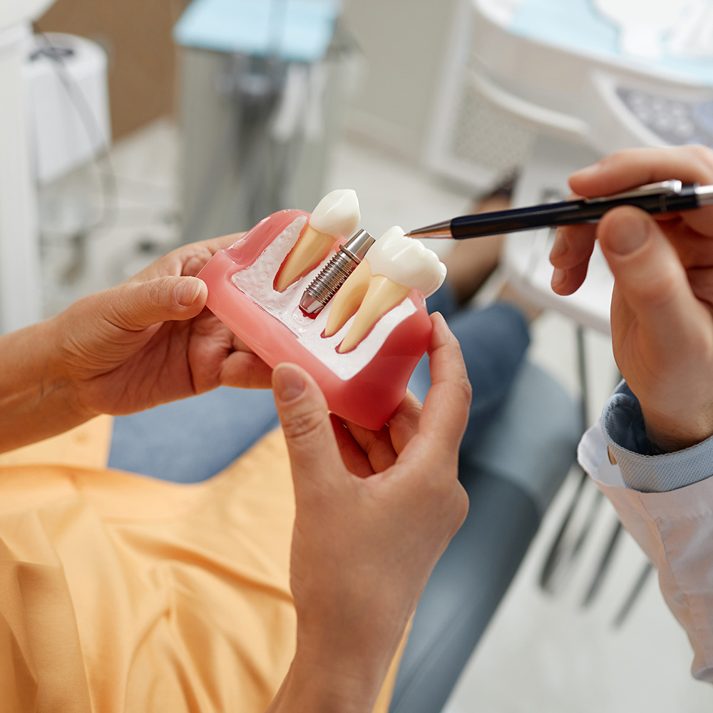 A dental professional examines a patient s teeth with a model set placed on a chair, likely for educational purposes.