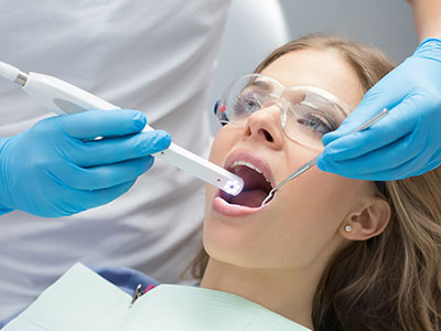 A dental professional using an electric toothbrush on a patient s teeth during a dental cleaning.